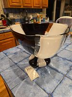 Full view of the black and white Vetri Murano art glass bowl on a tiled countertop, showcasing the shape and color pattern.