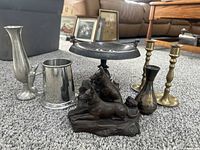 Front view of all items together on carpet, showing dessert stand with horse figurines, brass candle holders, pewter mug and vases.