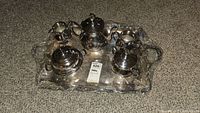 Full view of the 8 piece silverplate tea set wrapped in protective plastic showing all items on tray