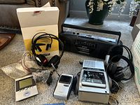 Group photo of all items showing Sony Watchman, Casio portable TV, UNISAR headphones, alarm clock, Sony cassette radio, and two headphone sets.