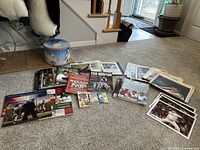 Overview of all items in the lot spread on floor with assortment of magazines, books, posters, trading card packs, and newspapers