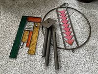 Photo showing metal and wood wind chime with circular frame and red wood pieces, metal tubes for chiming.