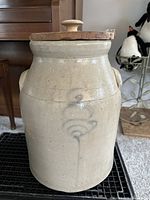 Front view of vintage stoneware crock with wood lid, showing blue decorative motif.