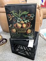 Closed vintage metal cake box with colorful fruit basket hand-painted on front panel, black metal with handle on top