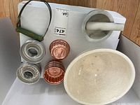 Overview of the vintage kitchenware lot showing mixing bowl, copper molds, tin molds, mortar and pestle, and pastry utensil.