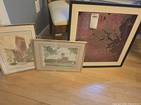 Photo of three framed Boston-related prints placed on floor against wall, showing relative sizes and styles.