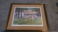 Full view of the framed watercolor print depicting golfers and spectators at a golf course in front of a clubhouse.