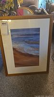 Framed seascape painting showing waves and sky, with wood frame and white mat.