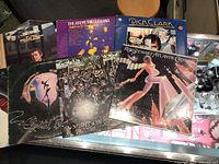 Photo showing seven vinyl albums stacked overlapping on a table. Visible album covers are Styx 'Crystal Ball', Rod Stewart 'A Night on the Town' and 'Atlantic Crossing', Steve Miller Band 'Children of the Future', Dick Clark compilation, Gordon Lightfoot, and Rick Wakeman.