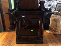 Front view of the antique medicine cabinet showing the glass door and carved wood design.