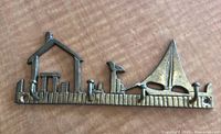 Brass key hook wall mount with dock and sailboat design shown on a brown surface