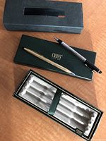 Two pens placed alongside original Cross pen box and insert on wooden surface