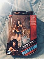 Front view of Wonder Woman 6-inch action figure sealed in packaging with visible sword and detailed costume.