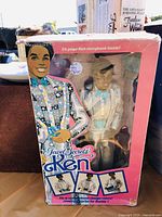Front of Jewel Secrets Ken doll box showing doll wearing colorful patchwork vest and bow tie, with 26-page Ken storybook included.