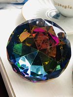 Close-up photo of the multi-colored crystal paperweight showing its diamond cut facets and color reflections.