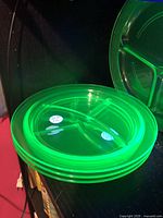 Stack of three Vaseline glass plates illuminated to show green fluorescence under UV light