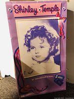 Original box front showing vintage Shirley Temple portrait and branding with purple and pink ribbon graphics