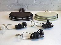 Five vintage lights on a white surface against white brick background, showing three black clip-on lights and two semi-circular headboard lights in brown and cream.