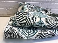 Folded Ikea curtain panels showing green and black leaf pattern on white fabric.