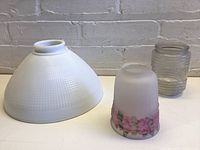 Set of three glass shades: large white milk glass textured shade, small painted frosted floral shade, and small clear ribbed jar-like shade.