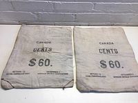 Two vintage Canadian cloth money bags side by side, showing markings for 60 dollars in cents and Royal Canadian Mint return instructions.