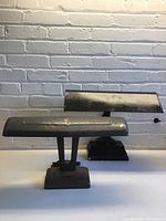 Two vintage metal desk lamps, one black fluorescent and one grey LED converted, placed on a white surface against a white brick wall.