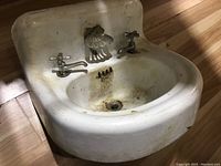 Front and top view of the white vintage enamel sink showing overall shape, enamel surface, basin, faucets, and splashback.