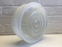 Side and top view of vintage milk glass light shade showing its opaque white color, ribbed sides, and circular textured pattern on base.