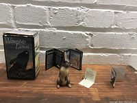 Figurine with original box and literature in background on wooden surface in front of white brick wall.