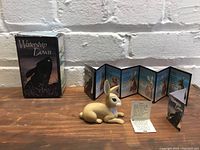 Photo of the ceramic Clover rabbit figurine lying on a wooden surface with its box and informational cards in the background showing the Watership Down logo and character descriptions.