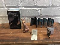 Figurine of Dandelion rabbit alongside Watership Down box and informational materials on table.