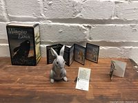 Front view of Silver ceramic figurine with original Watership Down box and pamphlets behind on wooden surface
