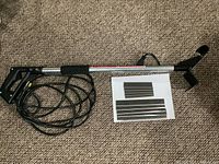 Floor scraper with long metal shaft, pistol-grip handle, power cord and blade sets on white paper