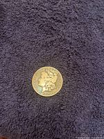 Obverse view of the 1878 CC silver dollar on dark fabric.