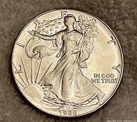 Obverse side of the 1986 US Silver Dollar Walking Liberty coin showing Lady Liberty walking with flowing gown and rising sun, inscribed LIBERTY and year 1986.