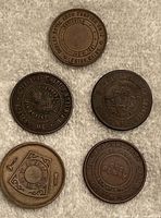 Top-view of five Masonic large cent coins arranged on a light fabric. Coins show various lodge names and Masonic symbols related to Maine lodges.