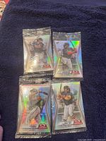 Four unopened 2024 Topps baseball card packs arranged on a dark blue cloth, showing Atlanta Braves players on the packaging.