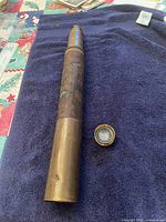 Full view of the antique brass telescope with one extending sleeve and separate lens on navy blue towel.