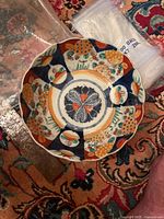 Top view photo showing the scalloped edge and floral pattern inside the bowl with colors blue, orange, green, and white.