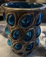 Close-up front view of the water glass showing the blue jeweled glass and silver-toned metal overlay detailing.