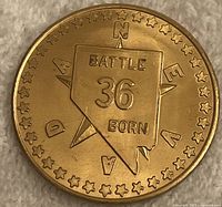 Obverse of brass medallion showing Nevada state outline with 'BATTLE 36 BORN' and surrounding stars with 'NEVADA' lettering.