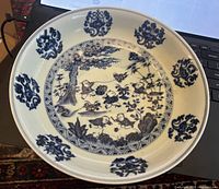 Top-down view of the reproduction Ming Dynasty bowl showing children's tale imagery with blue designs on off-white.