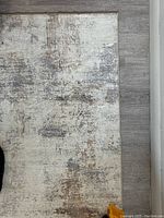 Close-up showing texture and abstract pigmentation of the rug on light wood floor.