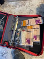 Photo of black and red zippered binder organizer containing metal rings and three packs of Up & Up brand pencils inside