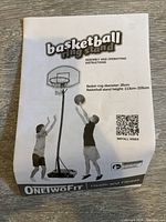 Assembly and operating instructions for the OneTwoFit basketball ring stand showing product details and adjustable height.