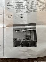 Instruction sheet showing specifications of the modern dimmable LED chandelier, including wattage 55W, voltage 100-265V, brightness adjustment, and a photo of the chandelier installed above a dining table.