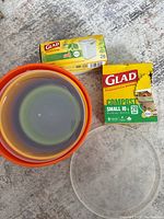 Set of 5 mixed size plastic mixing bowls nested, two boxes of Glad brand bags (trash and compost) on the floor.