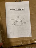 User manual front cover showing line drawing of the retractable ceiling fan with light and cage design.