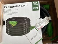 Box showing brand name, product name, and image of the extension cord coiled with green plugs.