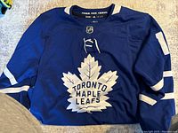 Front view of blue Toronto Maple Leafs hockey jersey with leaf logo.